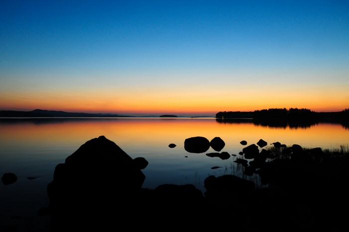 Sunset over a lake with rocks and trees