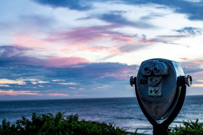 Coin-operated binoculars overlooking the ocean at sunset