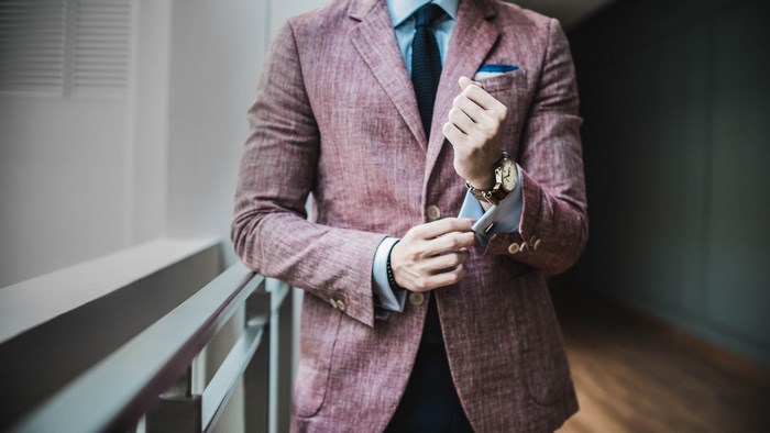 Man in a pink suit adjusting his cufflinks