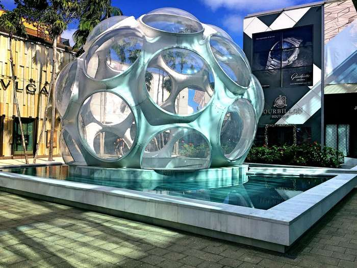 Futuristic glass dome fountain in front of luxury shops