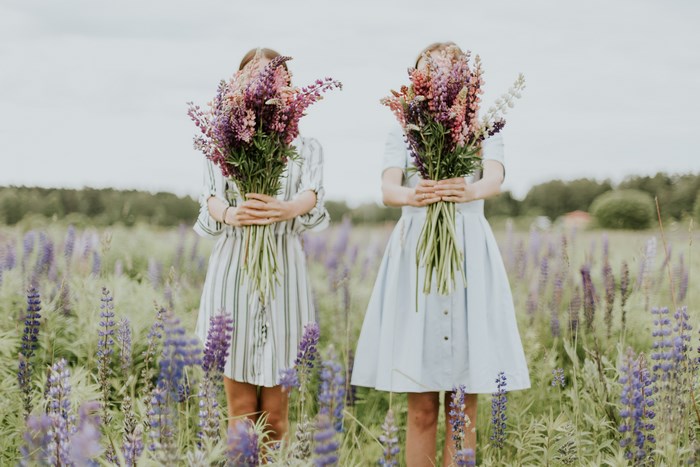 Two women holding bouquets of flowers in a field