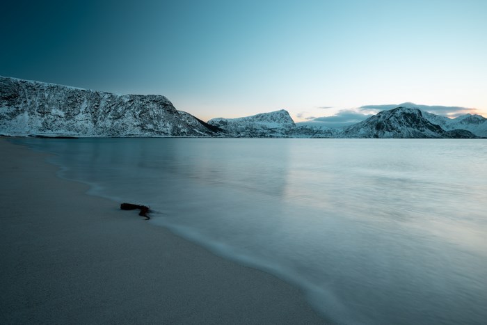Long exposure of snowy mountains and beach in Lofoten, Norway