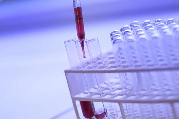 Pipette dropping liquid into test tubes in a rack