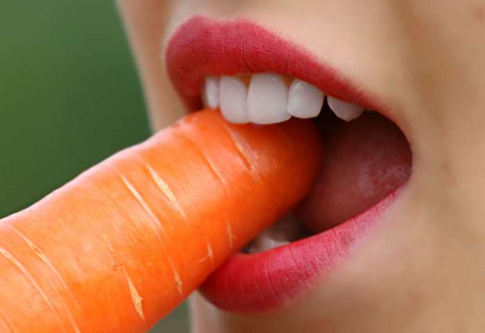 Close-up of person biting a carrot