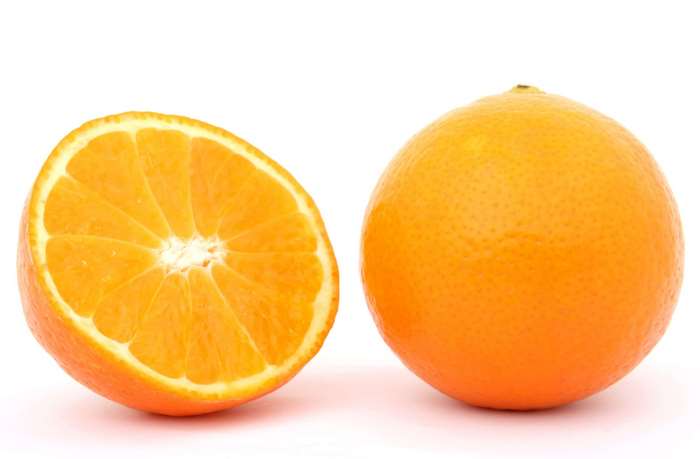 Whole and halved oranges on a white background