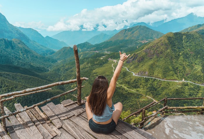Woman on wooden platform overlooking mountain valley