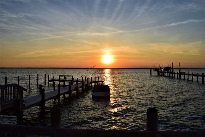 Sunset over the water with docks and a boat