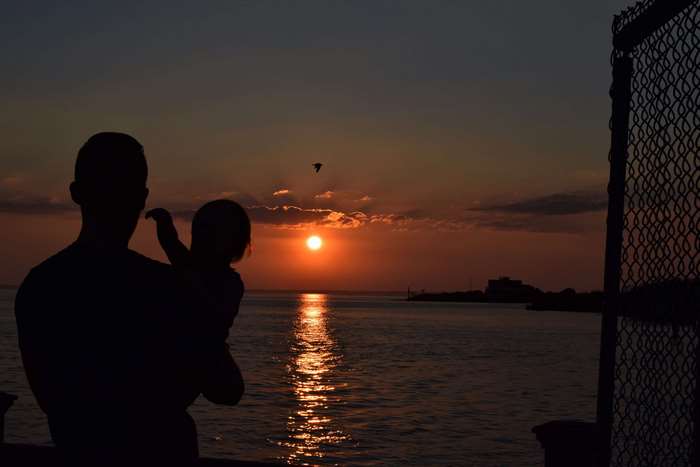Father and child watching sunset over the ocean