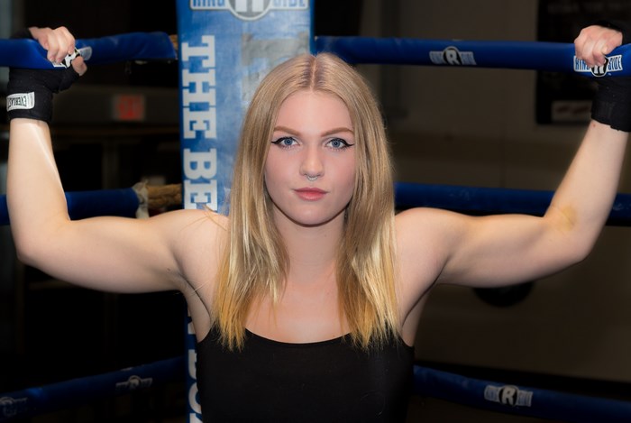 Confident athletic woman flexing in boxing ring
