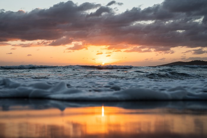 Sunset over the ocean with waves and clouds