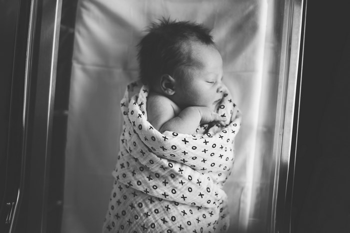 Newborn baby sleeping swaddled in a bassinet