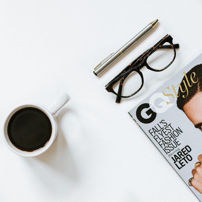 GQ magazine with coffee, glasses, and pen