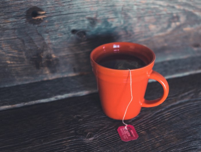 Orange mug of white tea on a wooden surface