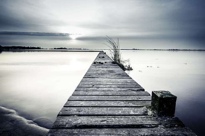 Wooden pier extending into a calm lake at sunset