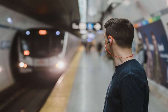 Man with earphones on a train station platform