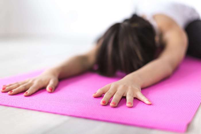 Woman doing yoga on a pink mat
