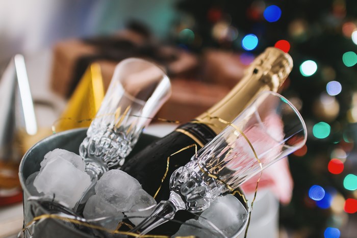 Champagne bottle and glasses in ice bucket with Christmas lights