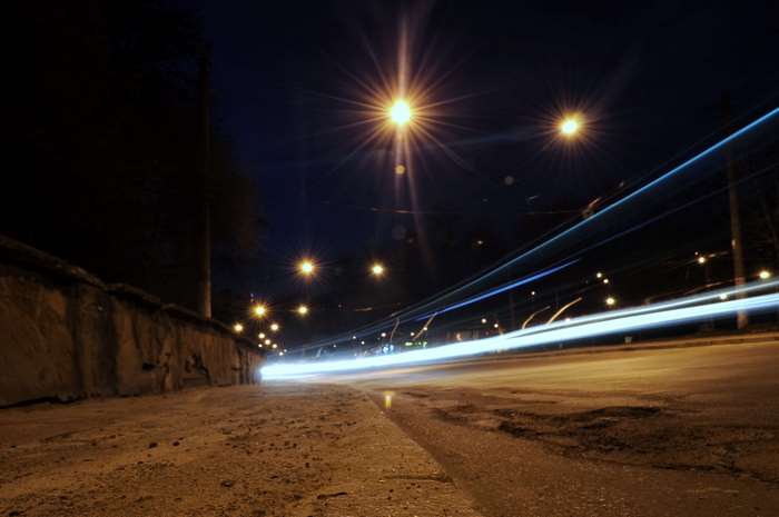 Night road with car light trails and streetlights