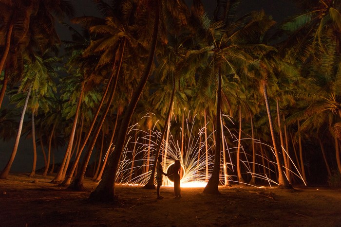 Couple with sparks among palm trees at night