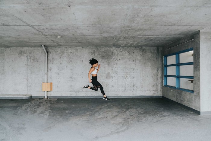 Woman in Nike running gear jumping in concrete room