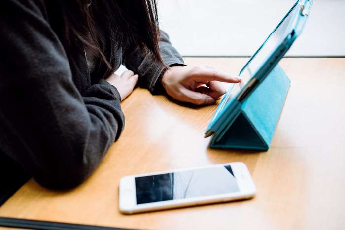 Person using tablet and smartphone on wooden table