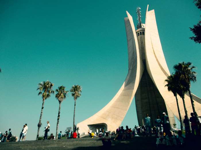 Monument in Algeria with people and palm trees