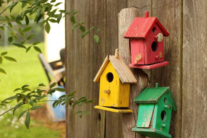 Three colorful birdhouses on a wooden fence