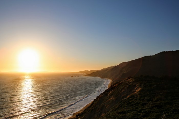 Sunset over the ocean coastline with hills