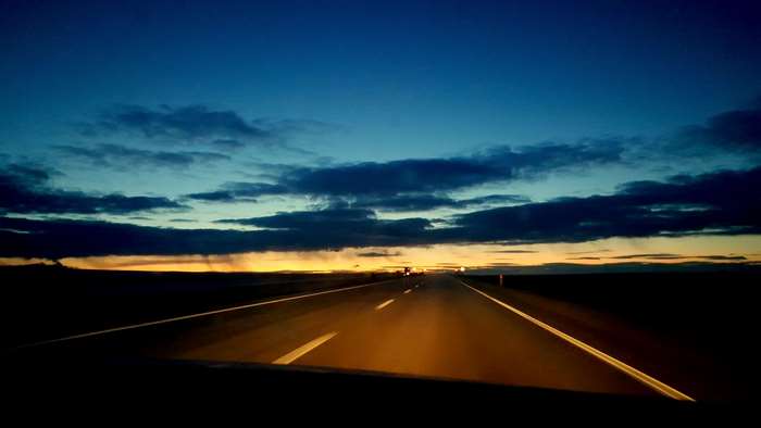 Road at sunrise with blue sky and clouds