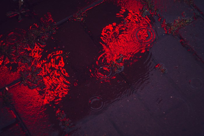 Red light reflection on wet pavement with ripples