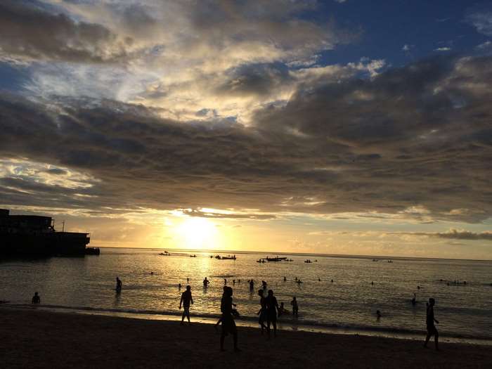 People on a beach at sunset with cloudy sky