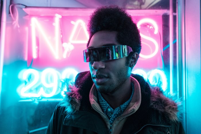 Man wearing futuristic glasses in front of neon sign