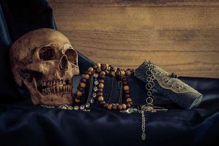 Skull with jewelry and stone on dark fabric