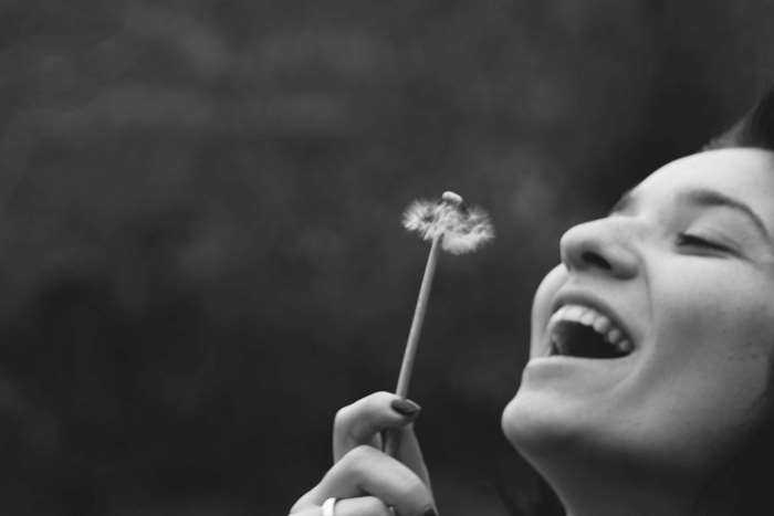 Woman blowing a dandelion in black and white
