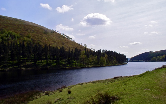 Reservoir surrounded by trees and hills under a cloudy sky