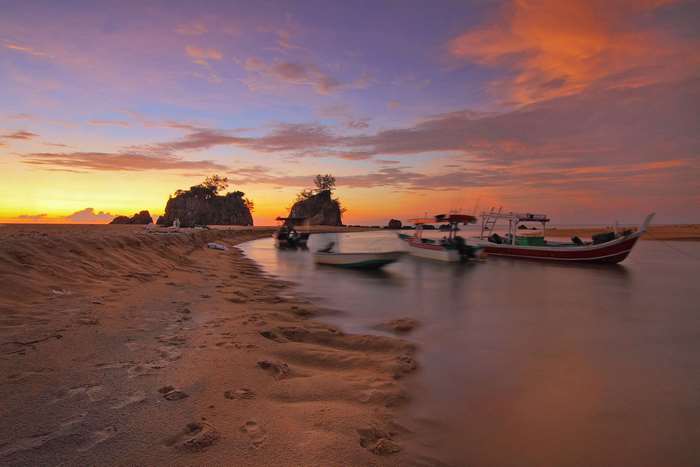Boats on the water at sunset with rocky islands
