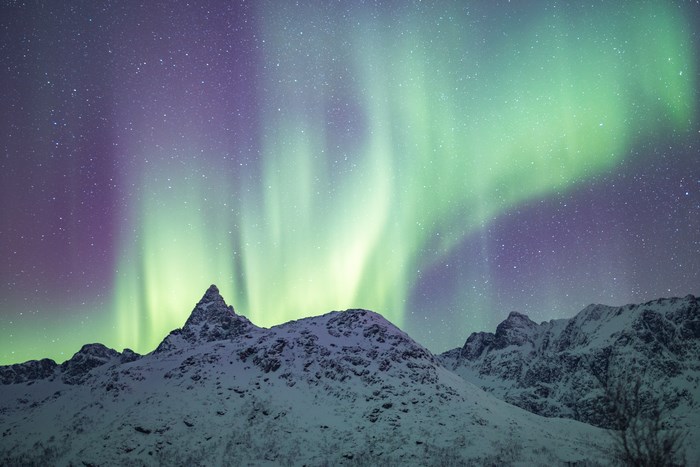 Aurora Borealis over snow-covered mountains in Norway