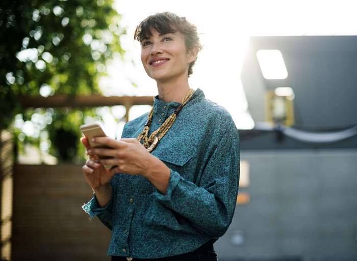 Woman in blue shirt holding a smartphone