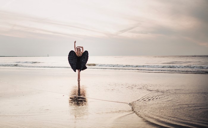 Woman with black wings on a beach