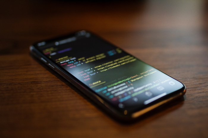 Smartphone Displaying Code On Wooden Desk
