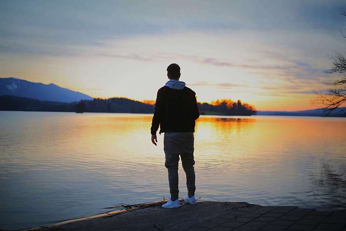 Man standing by a lake at sunset