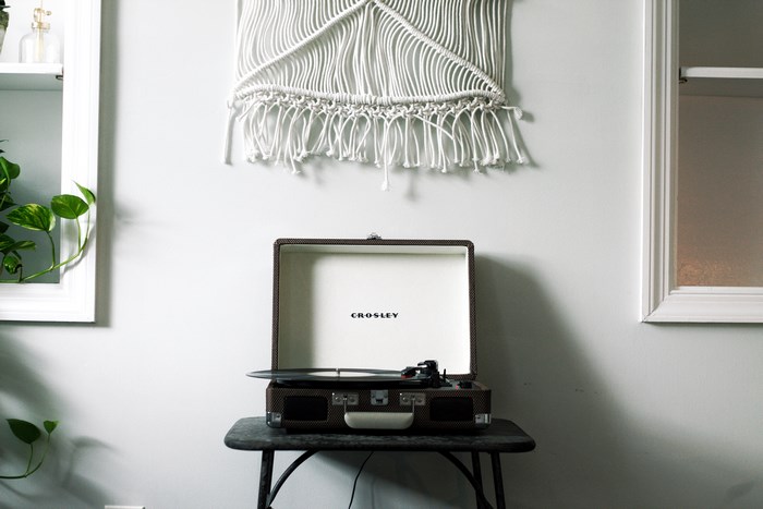 Crosley record player on a table with macrame wall hanging