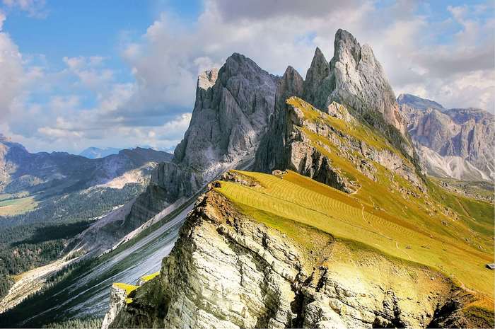 Jagged mountain peaks with green slopes under a cloudy sky
