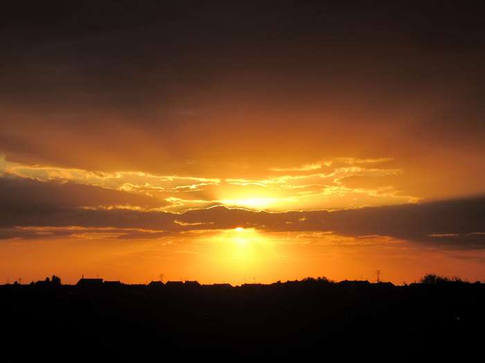 Sunset over a silhouetted town with dramatic clouds