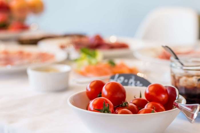 Bowl of cherry tomatoes on a table with food