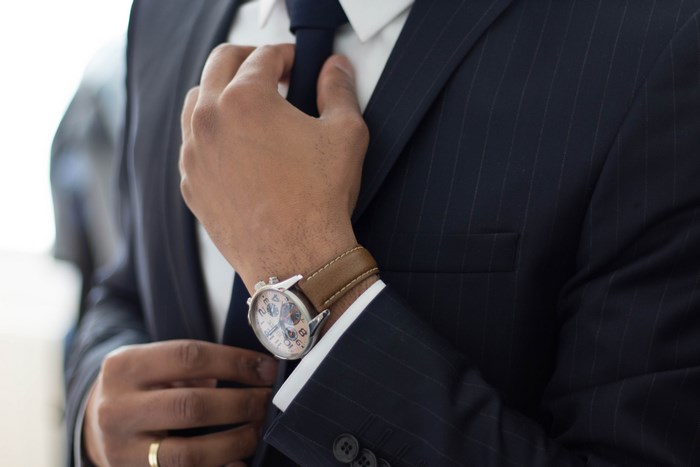 Man Adjusting Tie in Formal Suit with Watch