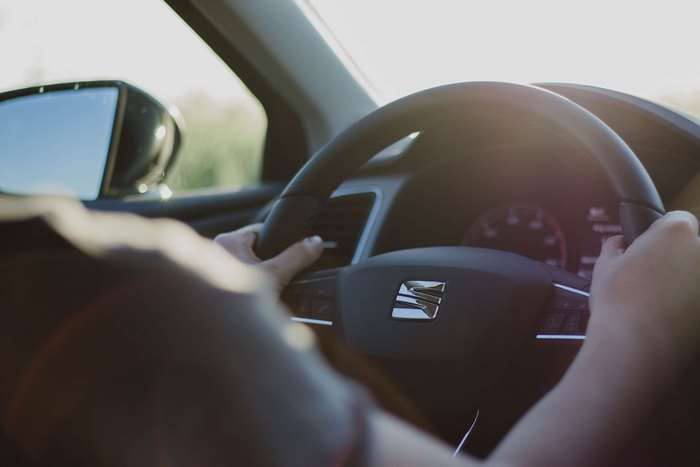 Person driving a car with hands on steering wheel