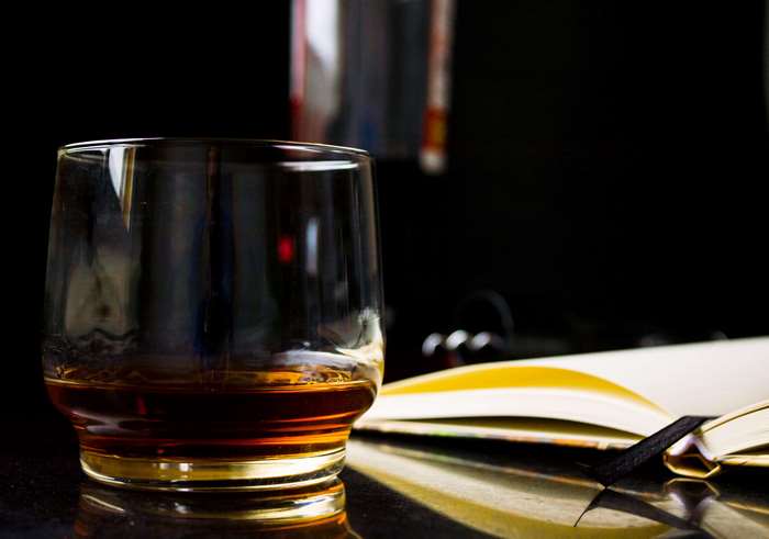 Whiskey in a glass next to an open book
