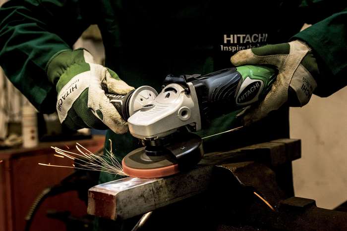 Person using a Hitachi angle grinder on metal