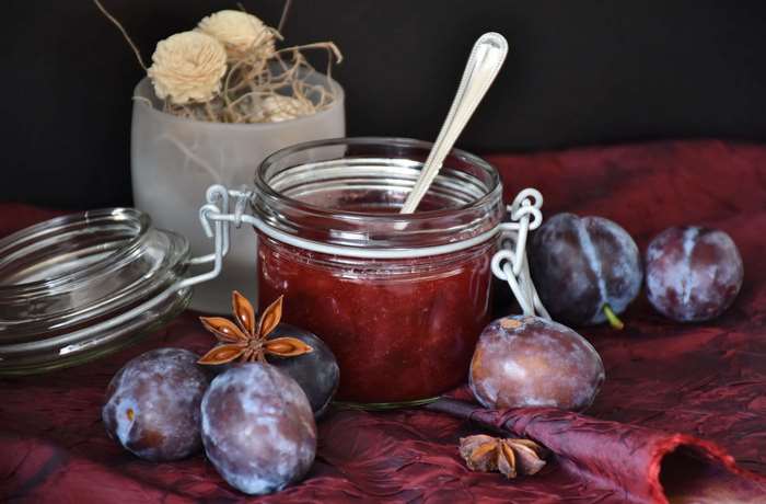 Plum jam in a jar with fresh plums and star anise
